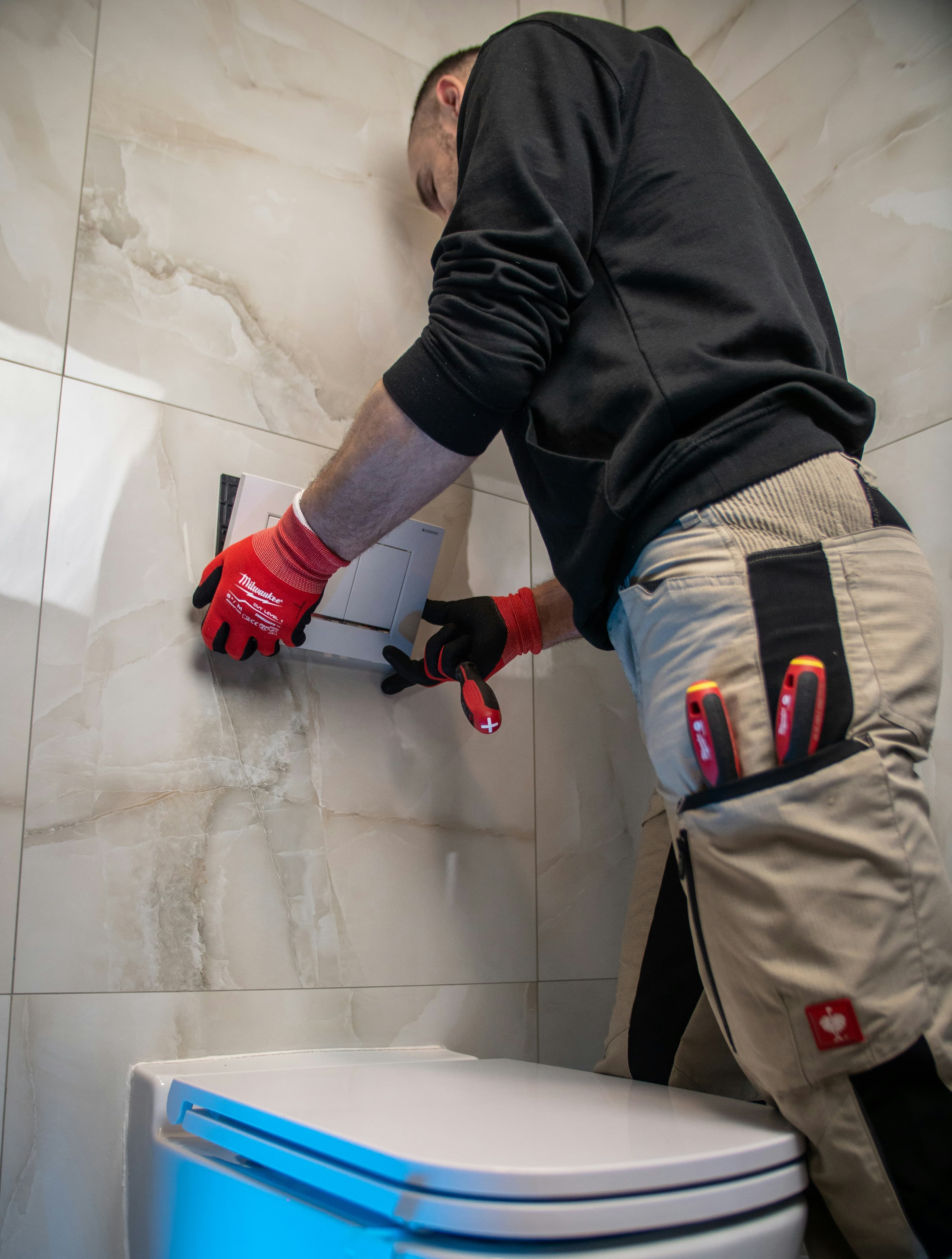 Contractor fitting a flush plate in a bathroom